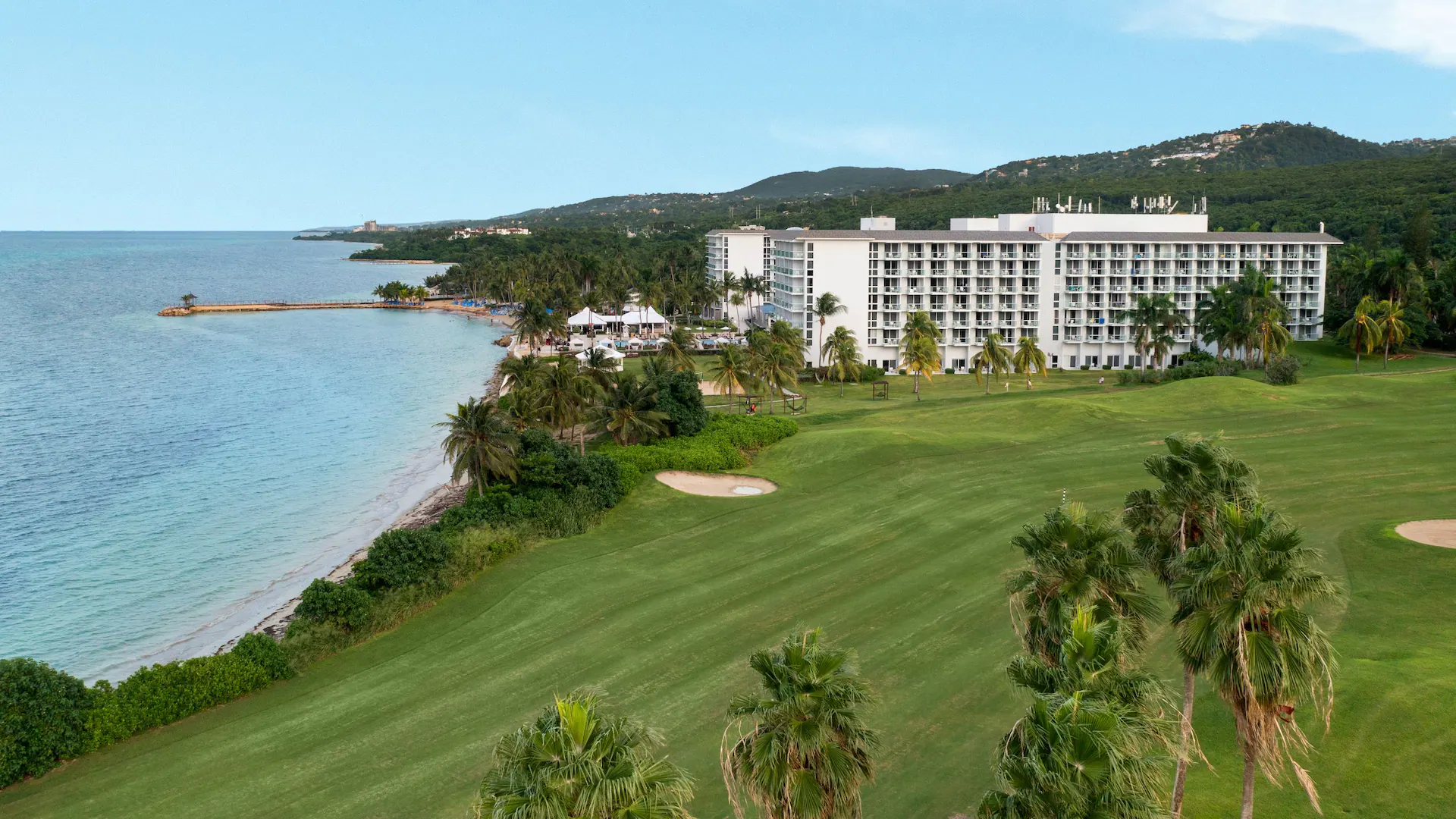 Aerial view of Dreams Rose Hall Resort & Spa beside a lush golf course and Caribbean coastline in Montego Bay, Jamaica.