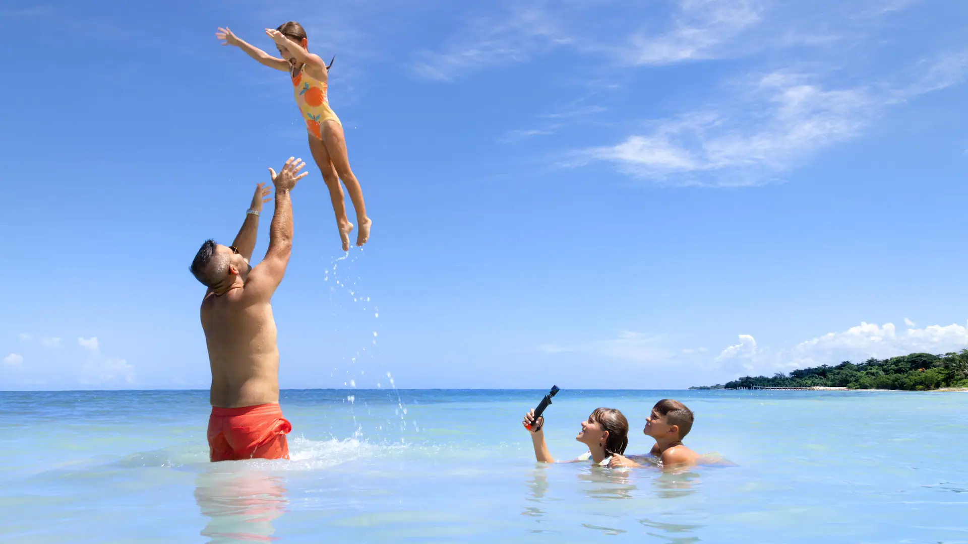 Family enjoying playful beach activities in the Caribbean waters at Dreams Rose Hall Resort & Spa in Montego Bay, Jamaica.
