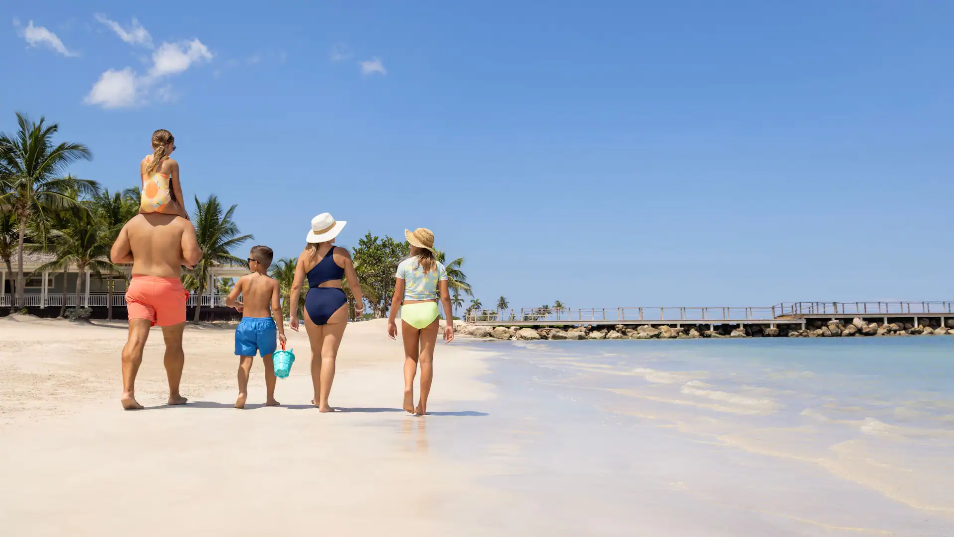 Family walking together along the sandy beach at Dreams Rose Hall Resort & Spa in Montego Bay, Jamaica.
