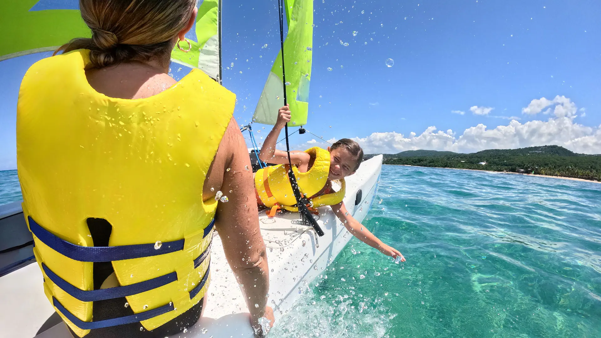 Family enjoying a Hobie Cat sailing adventure on the Caribbean Sea at Dreams Rose Hall Resort & Spa in Jamaica.