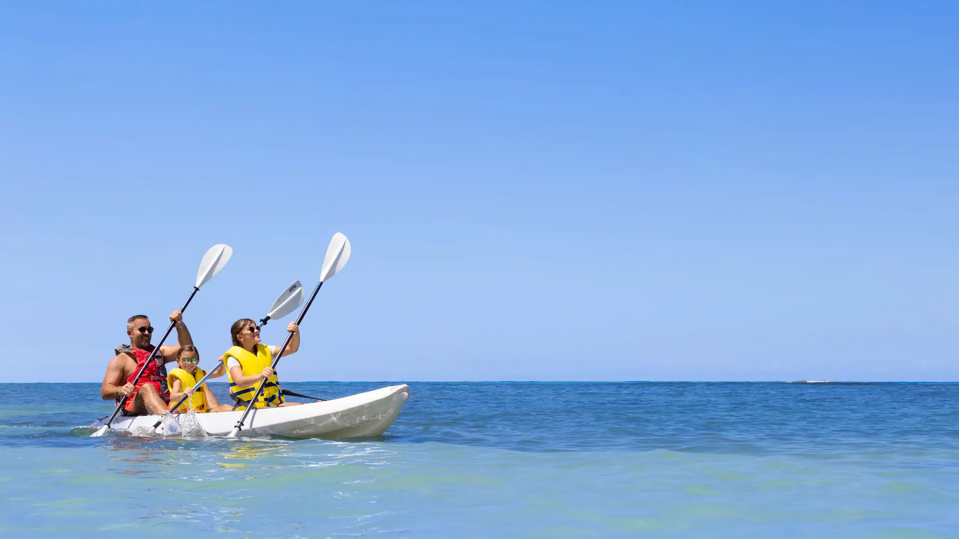 Family kayaking together on the Caribbean Sea at Dreams Rose Hall Resort & Spa in Montego Bay, Jamaica.