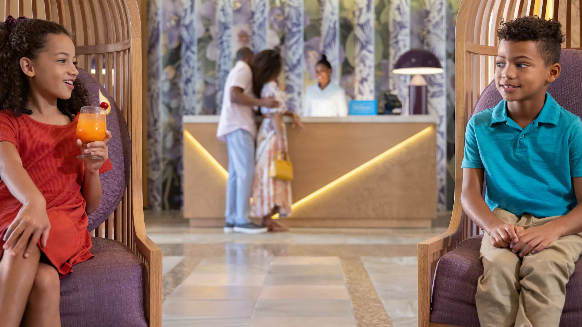 Children relaxing in the lobby at Dreams Rose Hall Resort & Spa while families check in for a Caribbean vacation in Jamaica.