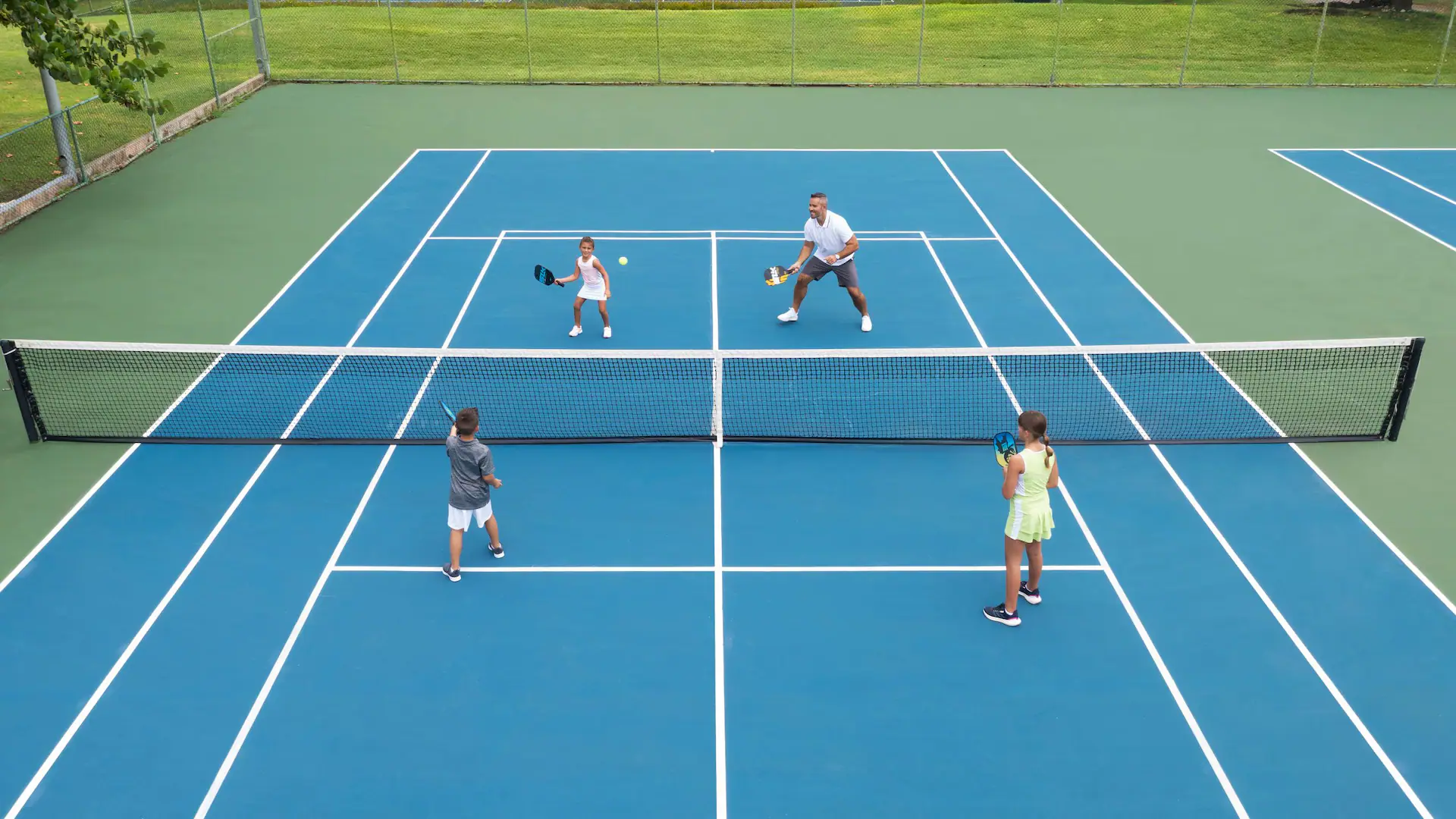 Father and children playing pickleball together at Dreams Rose Hall Resort & Spa in Montego Bay, Jamaica.