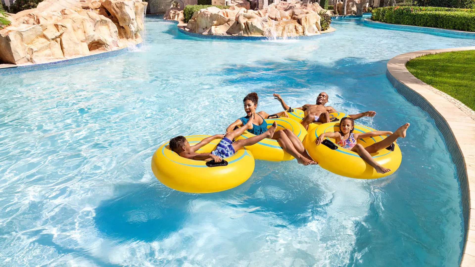 Family floating on tubes in the waterpark lazy river at Dreams Rose Hall Resort & Spa in Jamaica.
